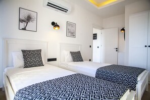 A hotel room with two beds, a white ceiling, and a door. - Lobelya Suites (Kaş)