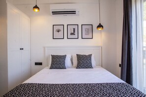Un dormitorio con una cama, dos almohadas estampadas, un cabecero blanco y tres cuadros en la pared.