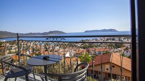 A balcony with a table and chairs, overlooking a coastal town with buildings and a clear blue sky. - Lobelya Suites (Kaş)