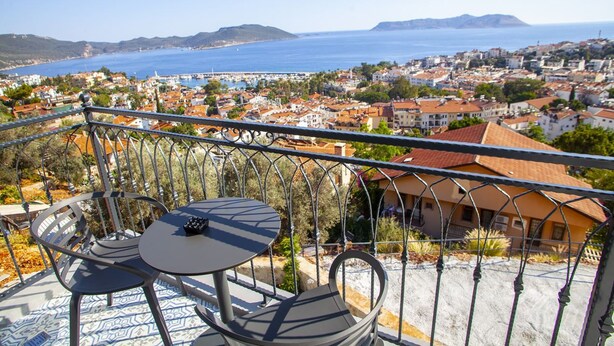 A balcony with a table and chairs, overlooking a coastal town with buildings and the sea. - Lobelya Suites (Kaş)
