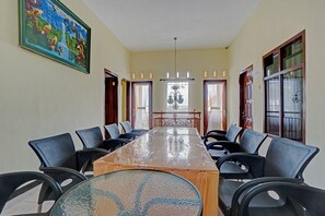 A conference room with a long table, black chairs, a chandelier, and a painting on the wall. - OYO 90488 Harwin Homestay (Batu)
