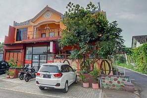 A two-story building with a balcony, a parked car, and potted plants. - OYO 90488 Harwin Homestay (Batu)