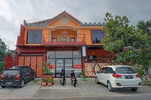 A two-story building with a balcony, a large window, and a gate. - OYO 90488 Harwin Homestay (Batu)