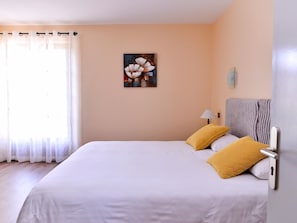 A hotel room with a bed, a painting on the wall, and a window with curtains. - Logis Hotel Le Chene Vert (Rocher)