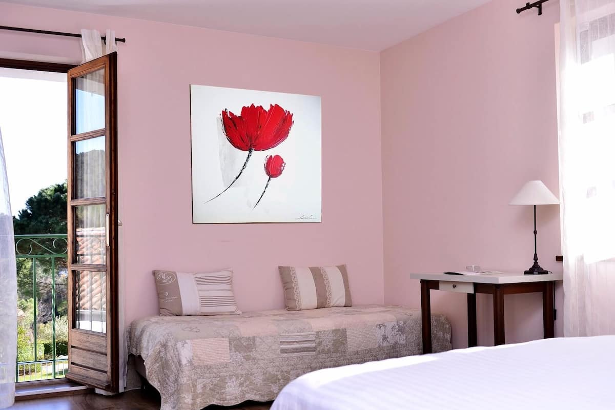 Un dormitorio con cama, mesita de noche, lámpara y ventana con cortinas.