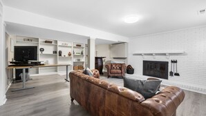 Een moderne woonkamer met een leren bank, een open haard en een televisie.