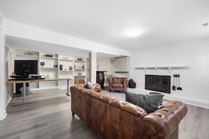 Un salon moderne avec un canapé en cuir, une cheminée et un téléviseur.