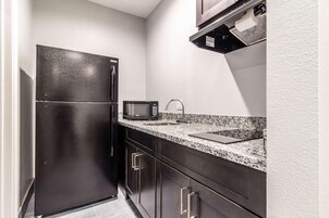 A compact kitchen with a black refrigerator, a microwave, and a sink.