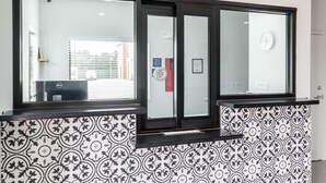 A reception desk with a patterned wall, a clock, and a door with a security sign. - Scottish Inns & Suites Kingwood (Kingwood)