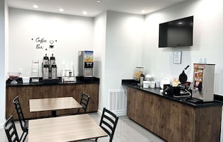 A coffee bar with a TV, seating area, and coffee machines.