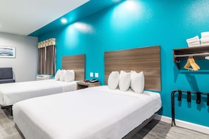 Ein Hotelzimmer mit zwei Betten, einem Schreibtisch, einem Stuhl, einem Kleiderständer und einem Wandbild.