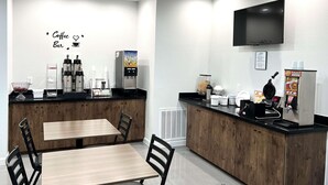 A coffee bar with a TV, seating area, and coffee machines. - Scottish Inns & Suites Kingwood (Kingwood)