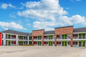 A multi-story motel with a central courtyard, individual rooms with balconies, and a parking area.