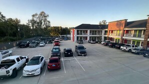 A parking lot with multiple cars and a building with balconies. - Scottish Inns & Suites Kingwood (Kingwood)