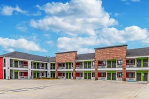 Un motel à plusieurs étages doté d’une cour intérieure, de chambres individuelles avec balcon et d’un parking.