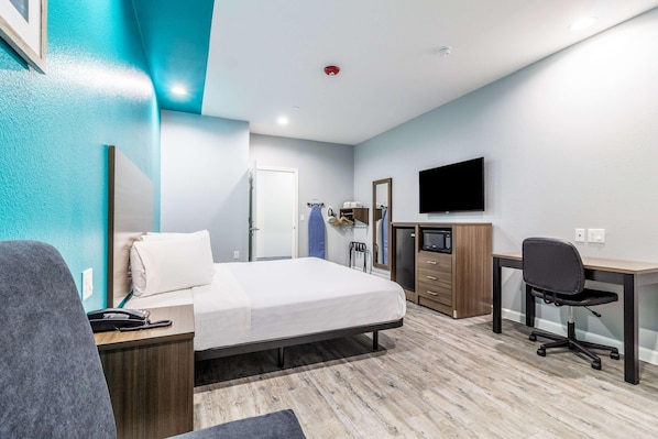 Une chambre d’hôtel équipée d’un lit, d’un bureau, d’une chaise et d’un téléviseur.