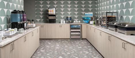 A modern kitchen with a patterned backsplash, a coffee machine, and a self-serve breakfast station.