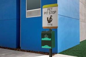 A pet waste disposal station with a sign that reads 'PET PIT STOP' and a green trash bin labeled 'Poopy Pouch.' - Home2suites by Hilton Miami Airport S. Blue Lagoon (Miami)
