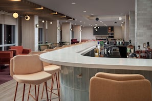 A modern bar area with a curved counter, bar stools, and a variety of liquor bottles. - Home2suites by Hilton Miami Airport S. Blue Lagoon (Miami)