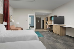 A hotel room with a bed, a desk, a television, and a kitchenette. - Home2suites by Hilton Miami Airport S. Blue Lagoon (Miami)