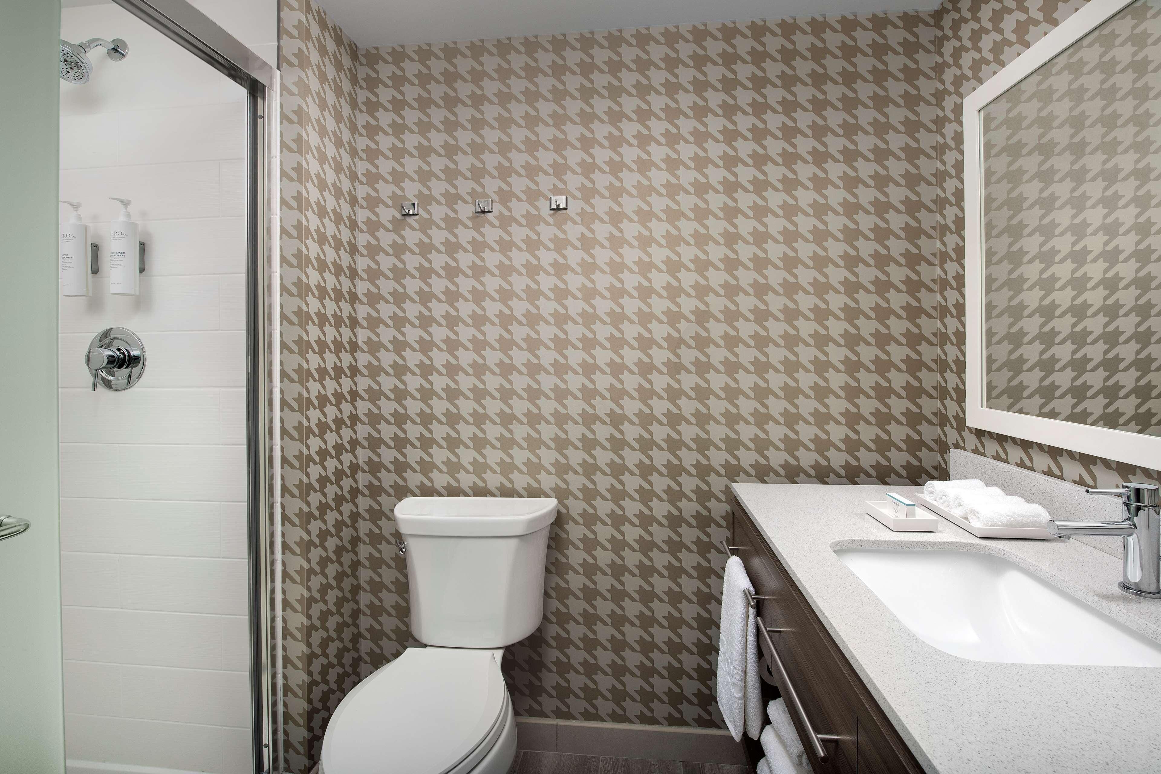 A bathroom with a shower, toilet, sink, and mirror.