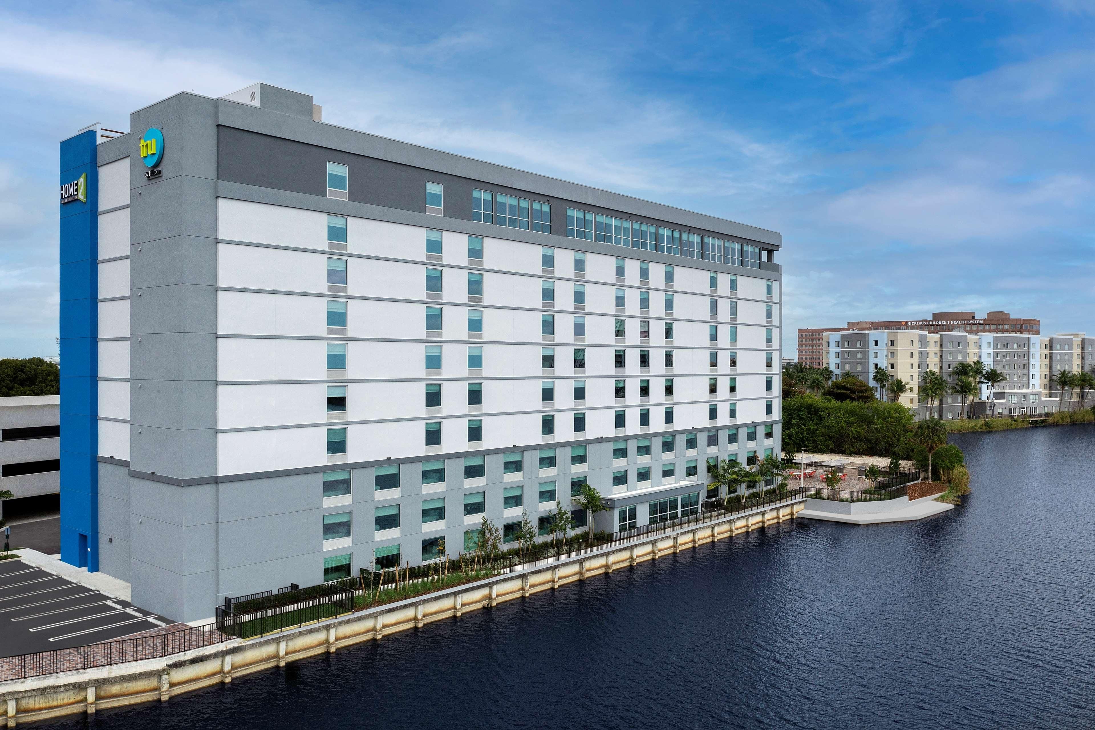 Un hotel moderno con gran número de habitaciones, zona de estacionamiento y vistas al agua.
