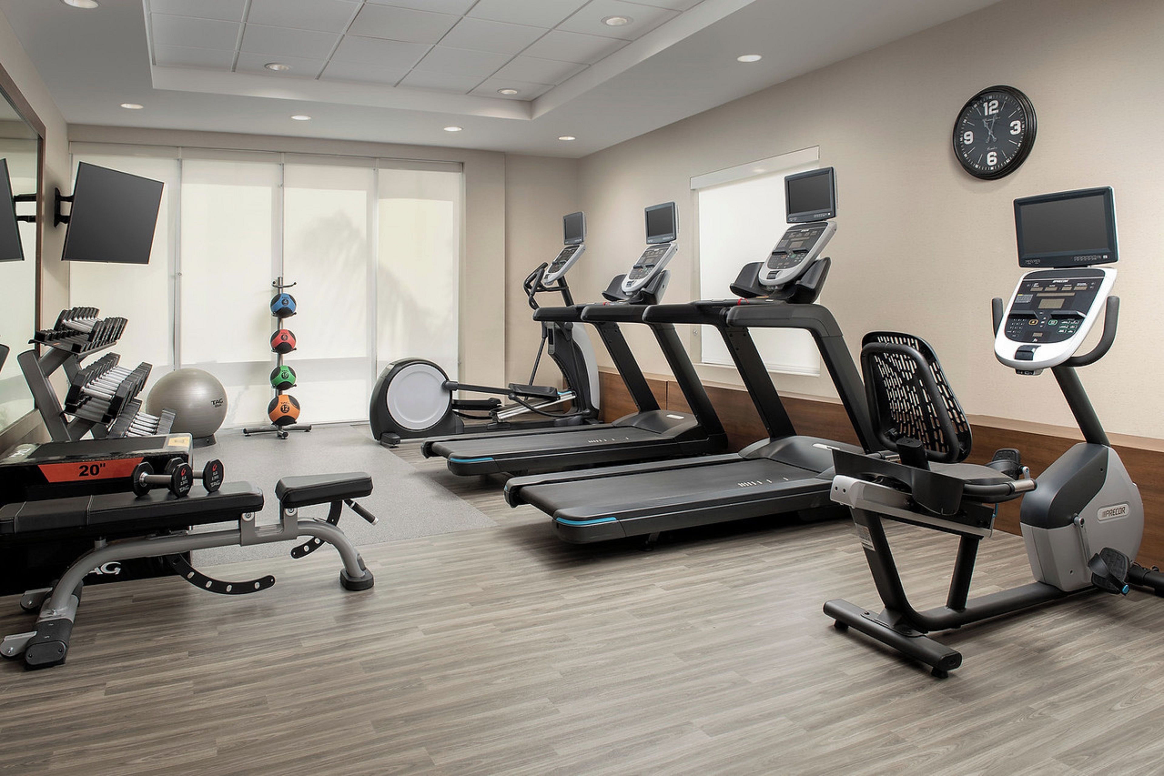 A gym with treadmills, a weight bench, and exercise balls.