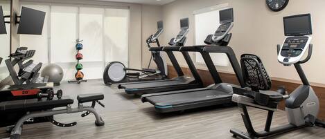 A gym with treadmills, a weight bench, and exercise balls.