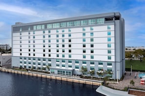 A modern hotel with a white facade, multiple floors, and a pool area with palm trees. - Home2suites by Hilton Miami Airport S. Blue Lagoon (Miami)