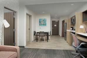 A hotel room with a dining table, chairs, a TV, and a microwave. - Home2suites by Hilton Miami Airport S. Blue Lagoon (Miami)
