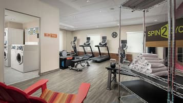 A hotel gym with exercise equipment, a laundry area, and a sign for Spin2Go.