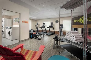 Ein Fitnessraum mit Trainingsgeräten, einem Waschbereich und einem Schild für Spin2Go.