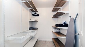 A walk-in closet with wooden shelves, a hanging rack, and a metal basket. - 2-Bedroom Home Away from Home in St Petersburg (St. Petersburg)