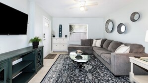 A living room with a TV, sofa, coffee table, and decorative mirrors. - 2-Bedroom Home Away from Home in St Petersburg (St. Petersburg)