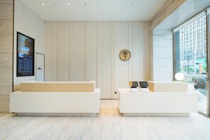 A modern reception area with a digital display, a wooden wall, and a large window offering a city view. - Ji Hotel (Jilin)