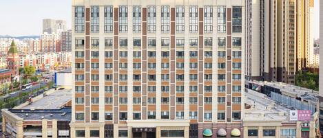 A multi-story hotel with a central entrance, multiple floors, and a parking area in front.