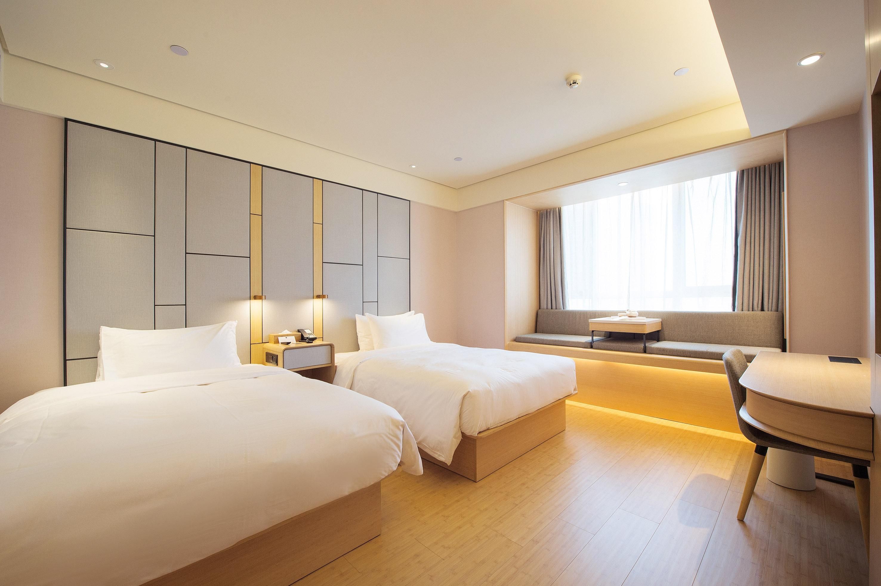 A hotel room with two beds, a seating area, and a large window.