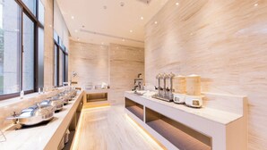 Uma cozinha de hotel moderna, com um balcão comprido, eletrodomésticos de aço inoxidável e vista pela janela.