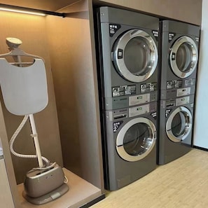 A laundry facility with two stacked washing machines and a drying machine. - Ji Hotel (Hefei)