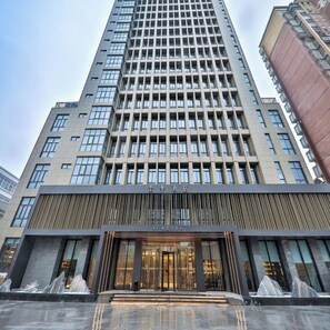 A modern hotel building with a prominent entrance, large windows, and a vertical design.