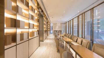 A modern hotel lobby with a long reception desk, seating area, and a wall with illuminated shelves.