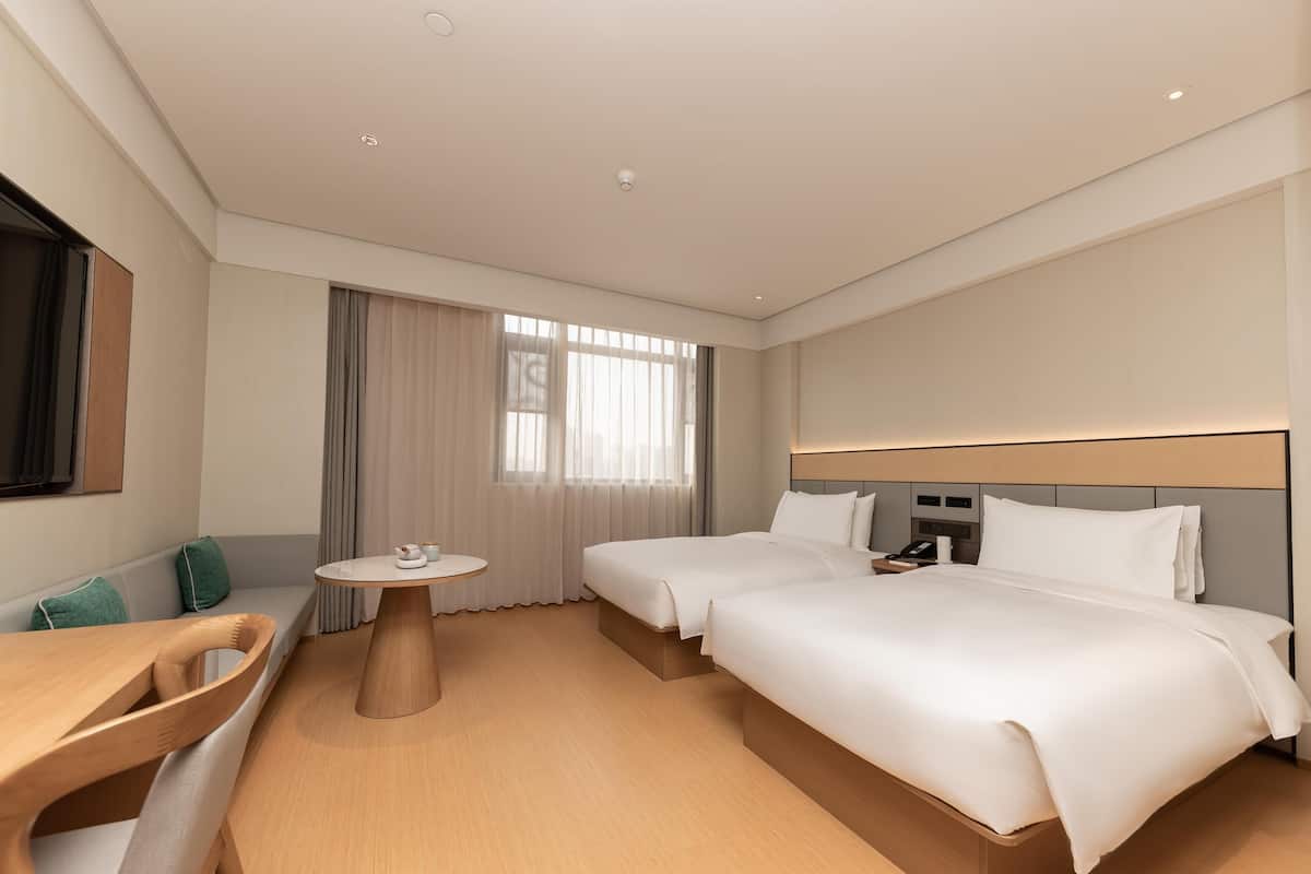 Una camera d'albergo con un letto, un comodino, una lampada e vista sulla città.