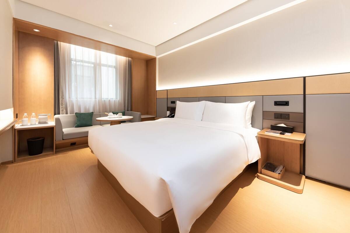 Una camera d'albergo moderna con un letto grande, comodini, una scrivania e una finestra con tende.