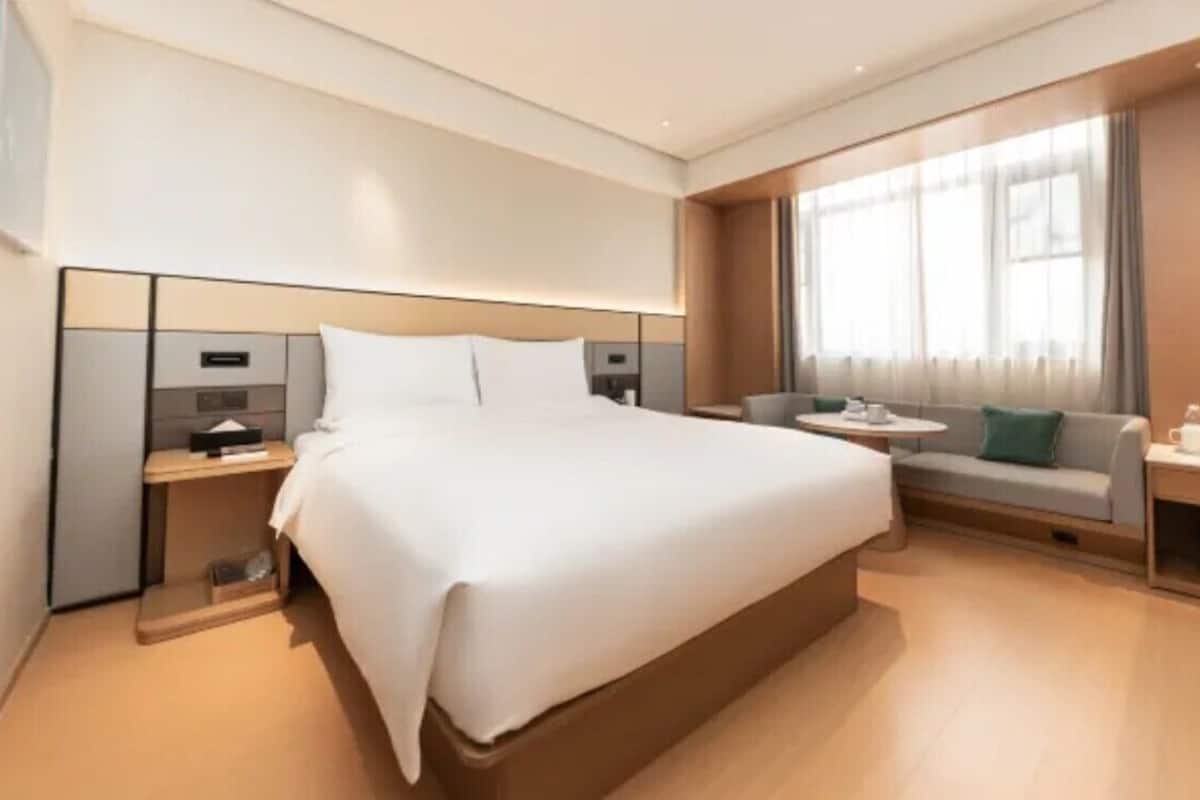 Una camera d'albergo moderna con un letto grande, un divano, un tavolino e una finestra con tende.