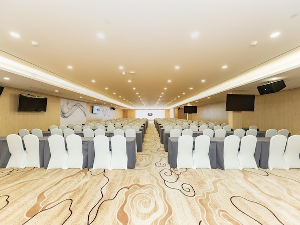 A conference room with rows of white chairs, a carpeted floor, and a large screen at the front. - Ji Hotel (Nanjing)