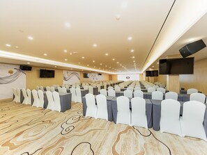 A conference room with rows of tables and chairs, a large screen, and a patterned carpet. - Ji Hotel (Nanjing)
