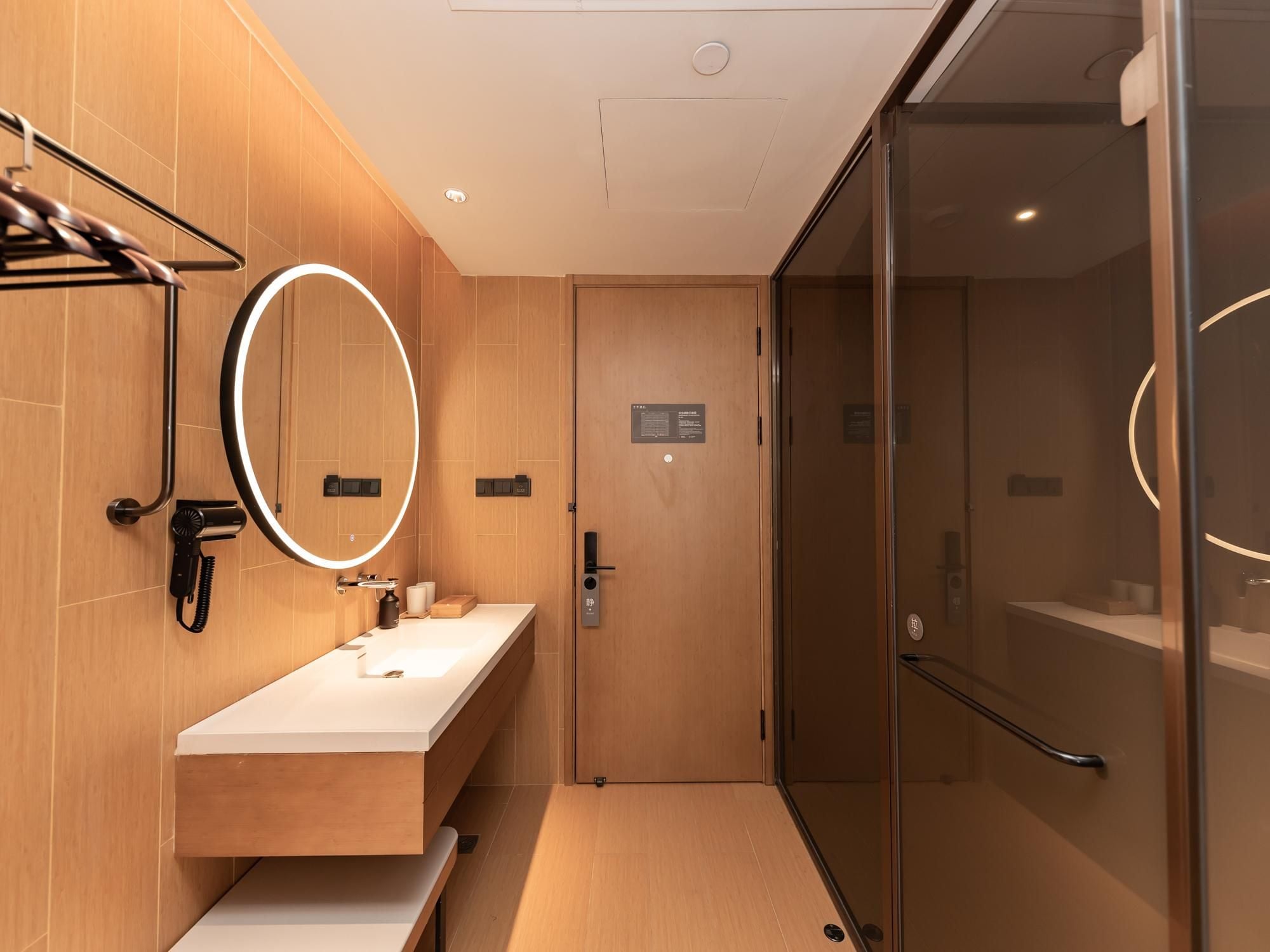 Un baño moderno con tocador, espejo, secador de pelo y cabina de ducha de vidrio.