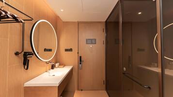 Un baño moderno con tocador, espejo, secador de pelo y cabina de ducha de vidrio.