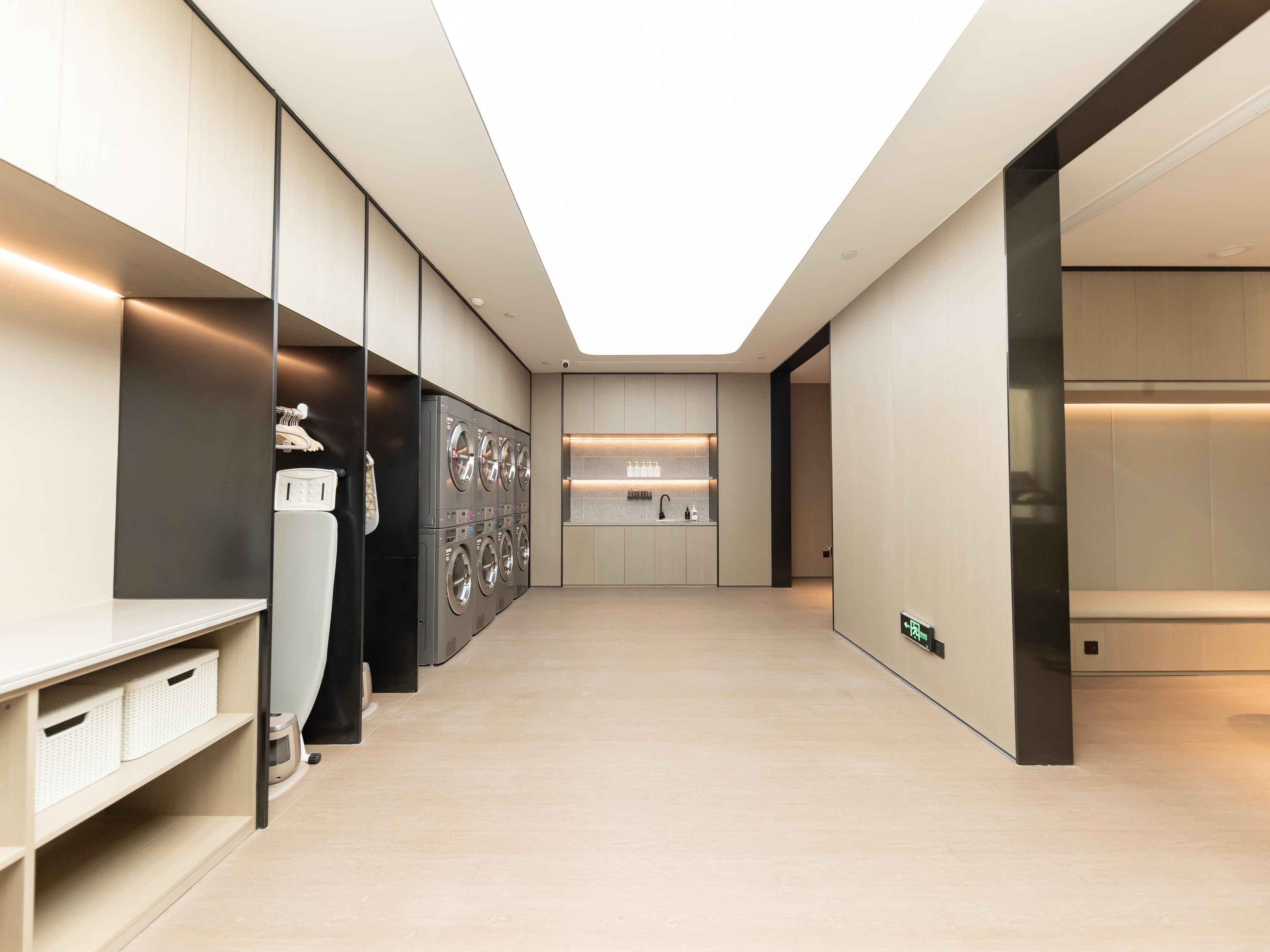 A modern hotel corridor with a central washing station, a kitchenette, and a reception area.