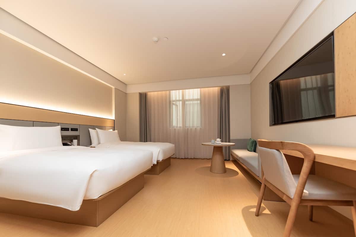 Camera d'albergo con un letto grande, una scrivania, una sedia, una TV e una finestra con tende.